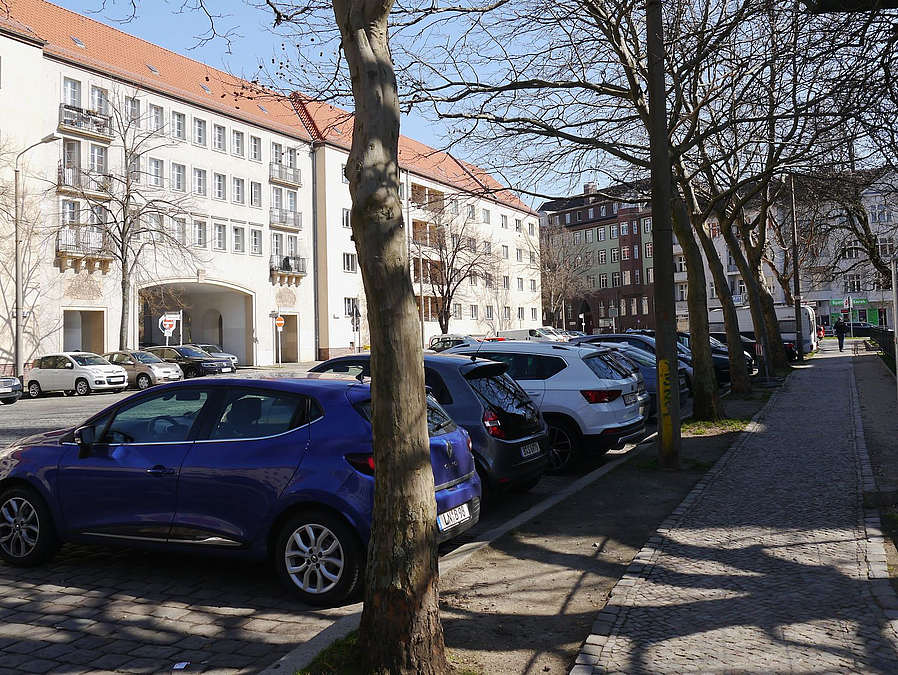 Parkende Autos unter Bäumen am Straßenrand