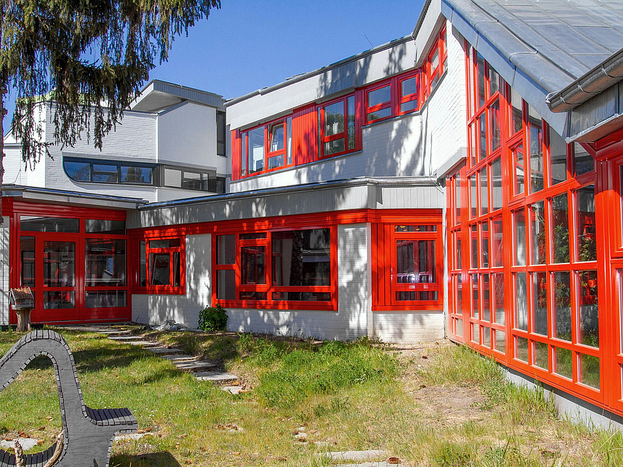 Übereck gebautes ein- bis zweistöckiges Gebäude mit roten Fenster- und Türrahmen