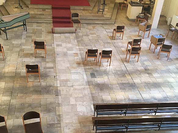 Blick von oben auf Boden aus Steinfliesen, Stühle, Kirchenbänke