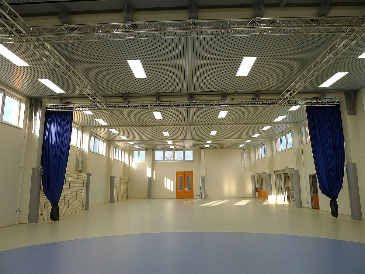 Blick in Sporthalle mit gerafften blauen Vorhängen an beiden Seiten