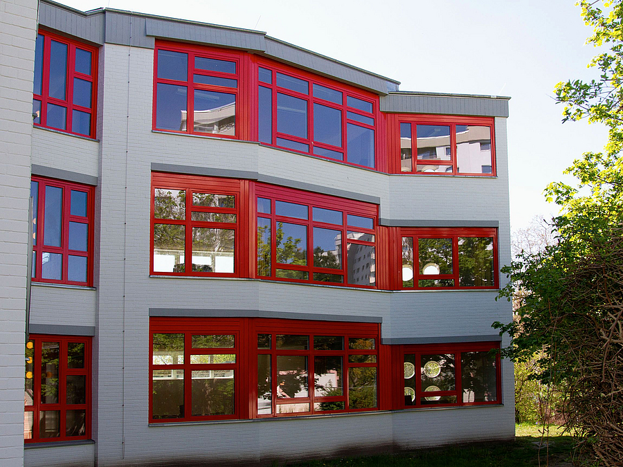 Dreistöckiges, weißes Gebäude mit roten Fenster- und Türrahmen