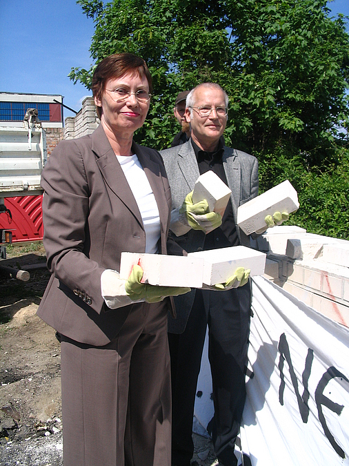Frau und Mann halten Kalksteine einer weißen Mauer in der Hand
