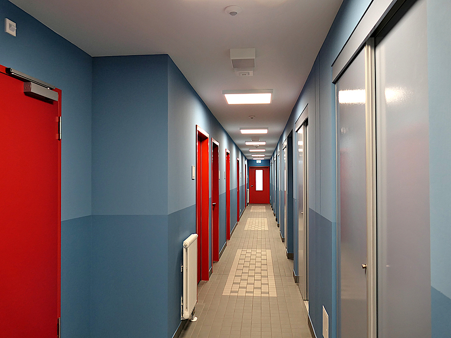 Schmaler Gang mit blauen Wänden und rote und grauen Türen