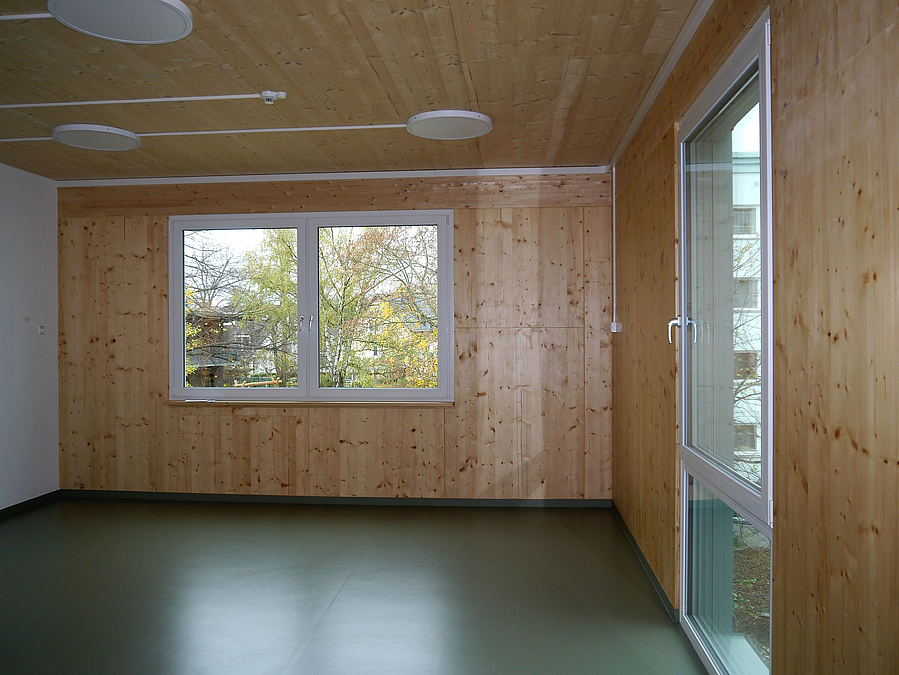 Raum mit holzgetäfelter Decke und Wänden an 2 Seiten, große Fenster