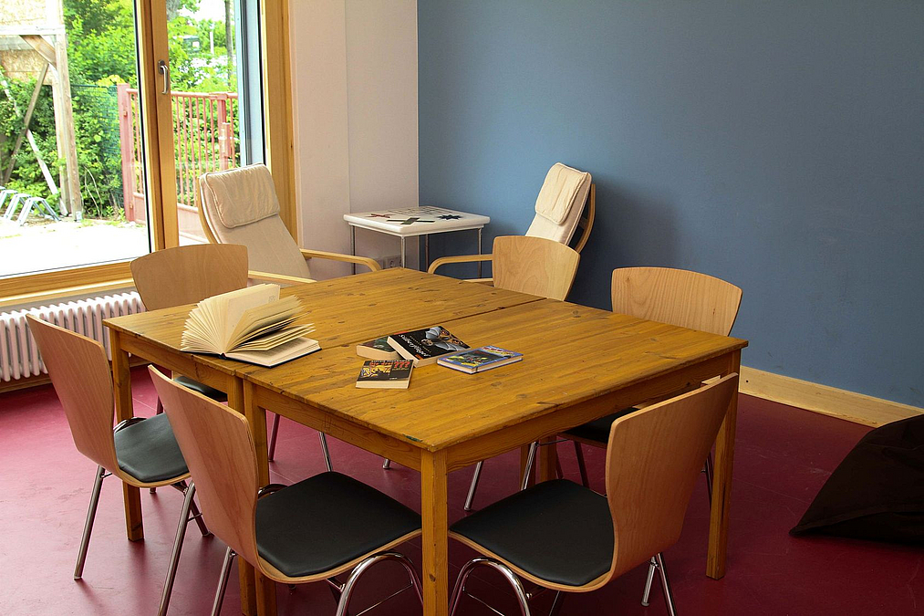 Holztisch und Stühle vor blauer Wand und bodentiefem Fenster