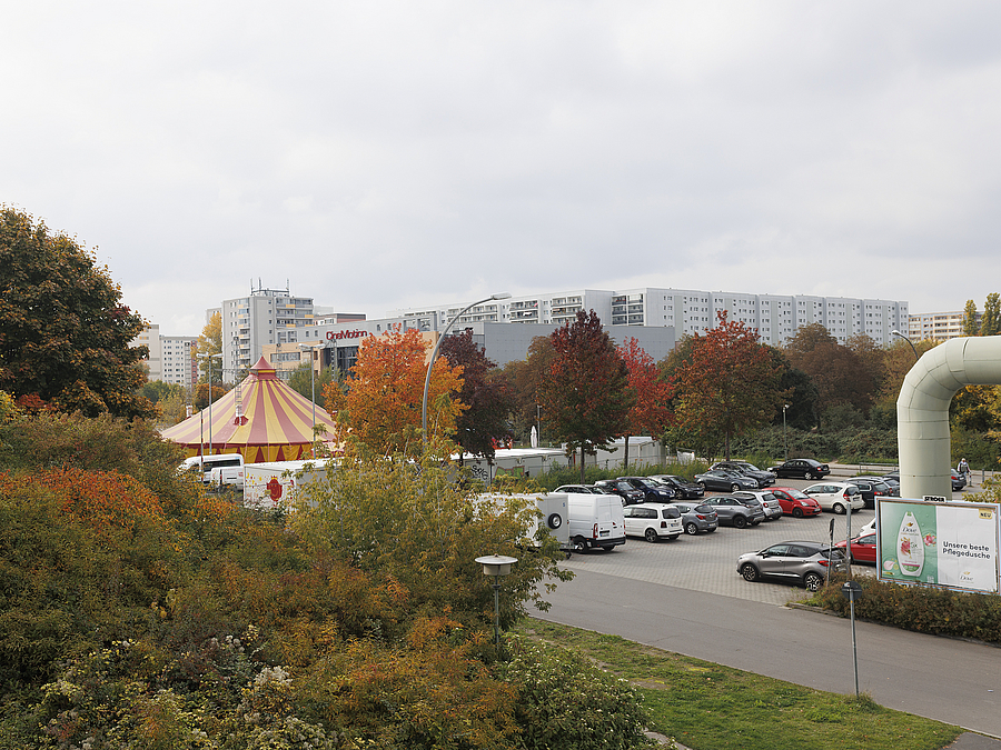 Parkplatz, im Hintergrund Plattenbaugebiet und Zirkuszelt
