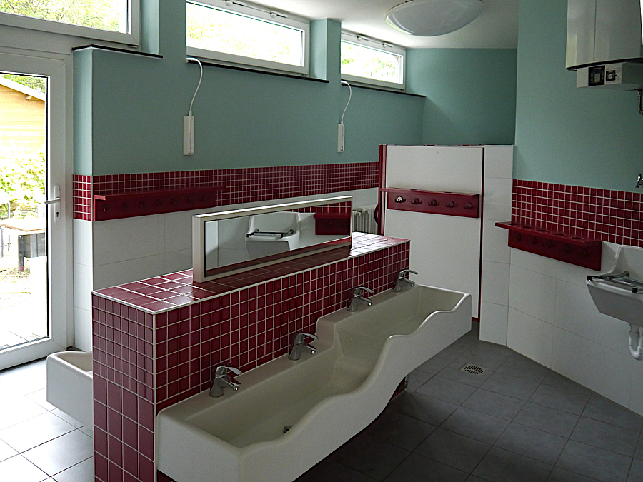 Sanitärraum mit stufenförmigem Waschbecken, rot-weiß gefliest, Wand in Baluton