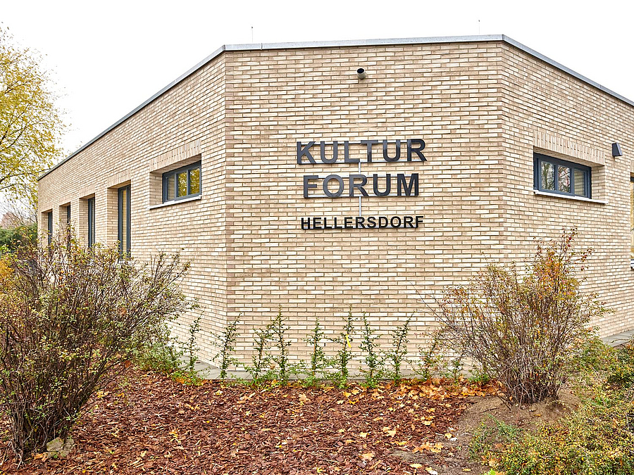 Klinkergiebel Flachbau mit Schriftzug "Kulturforum Hellersdorf", davor herbstliche Beete