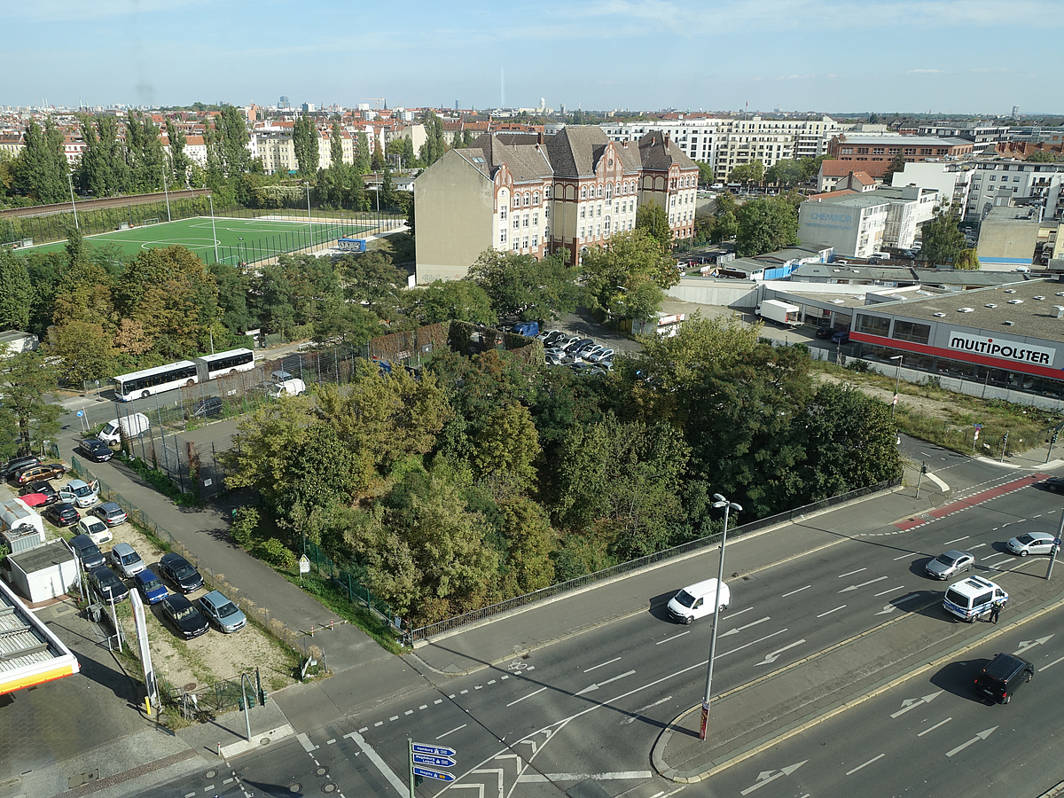 Luftbild mit Grünfläche und sechsspuriger Straße, Schule, Sportplatz, Gewerbe