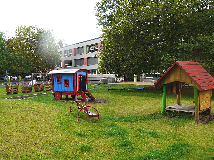 2 Spielhütten auf Rasen, im Hintergrund Gebäude