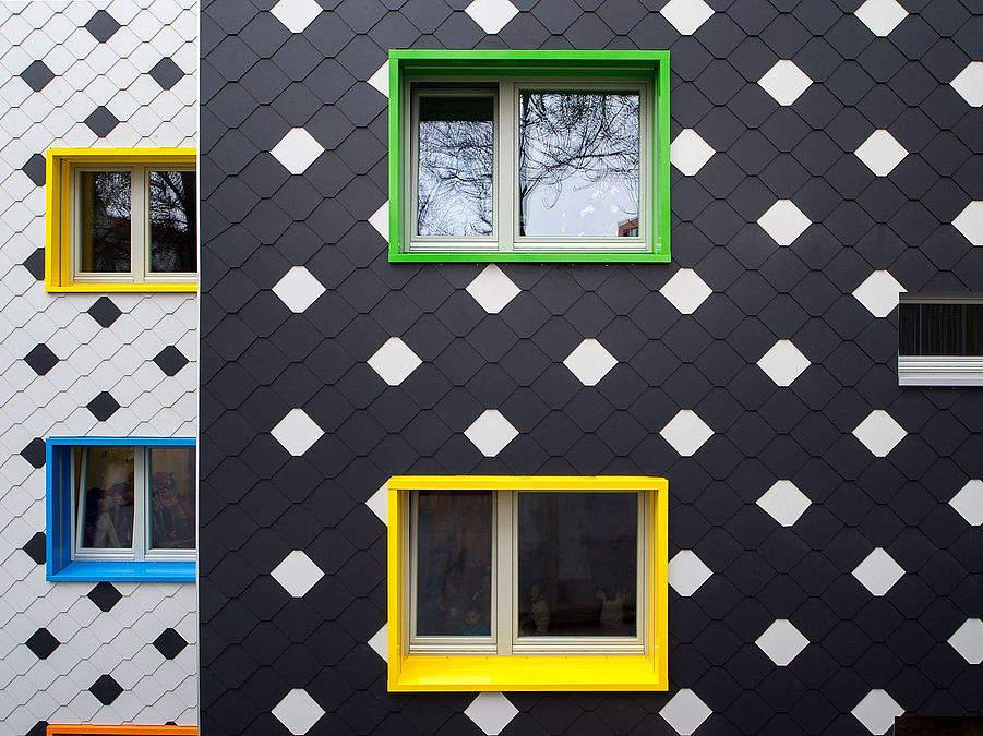 Detail: Fassade aus schwarzen (Front) und weißen (Quergebäude) Schindeln, mit der jeweils anderen Farbe als regelmäßiger Akzent, verschiedenfarbige Fensterlaibungen