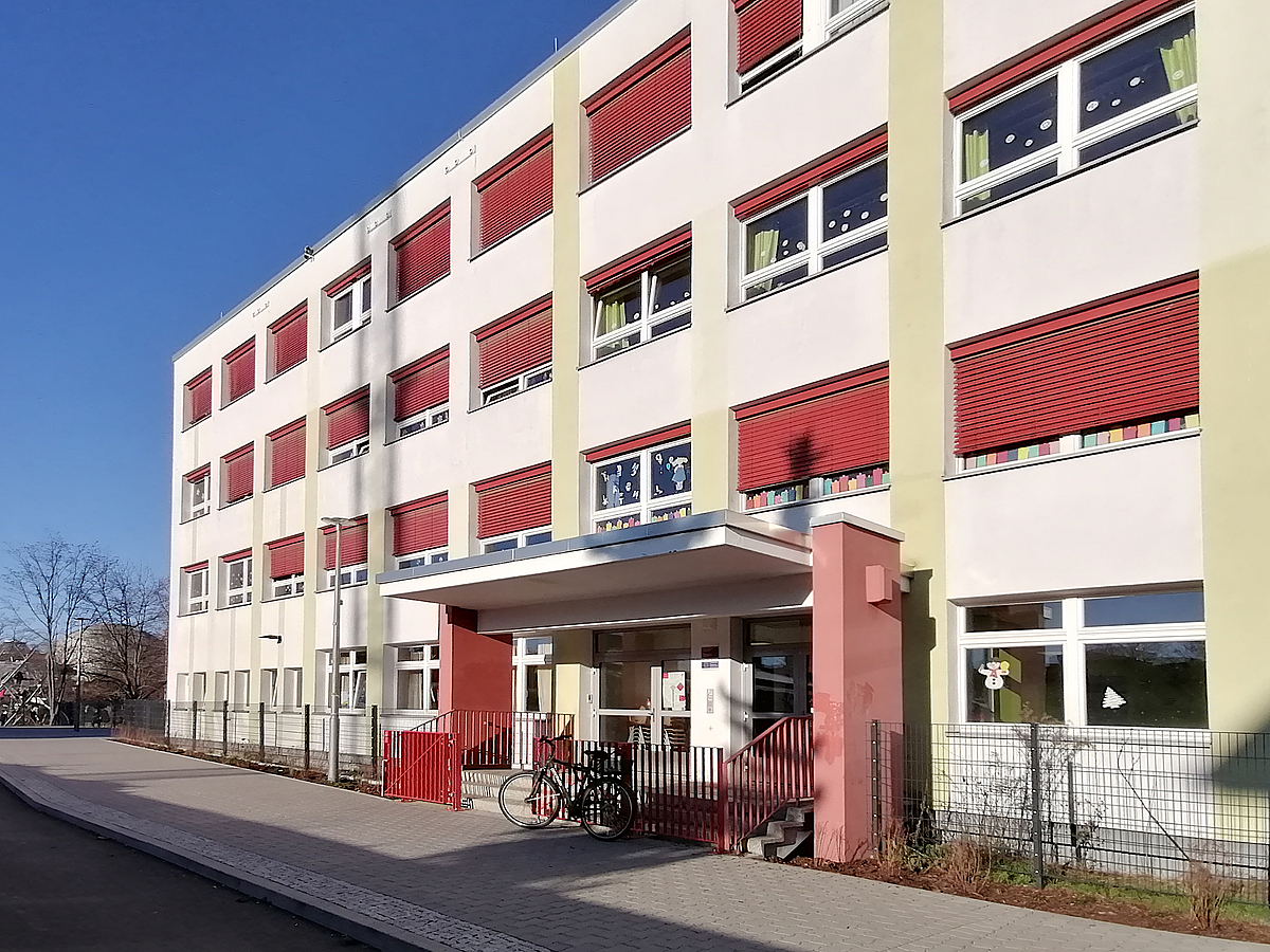 4-Geschossiges, helles, modernes Schulgebäude mit roten und hellgelben Akzenten