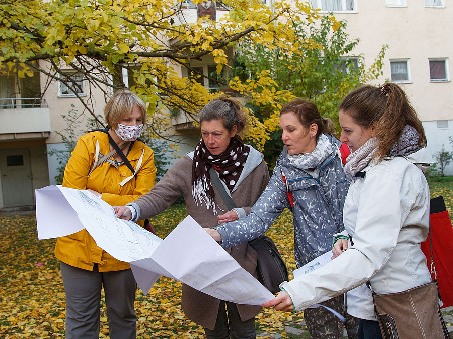 4 Frauen betrachten im Freien ein großes gefaltetes Papier