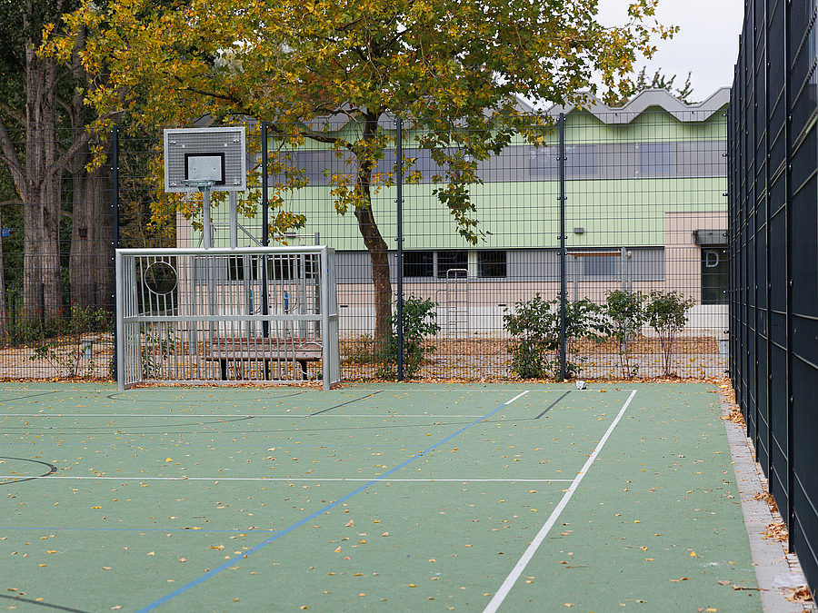 Ballspielplatz mit Ballfangzaun, Metalltor und Basketballkorb