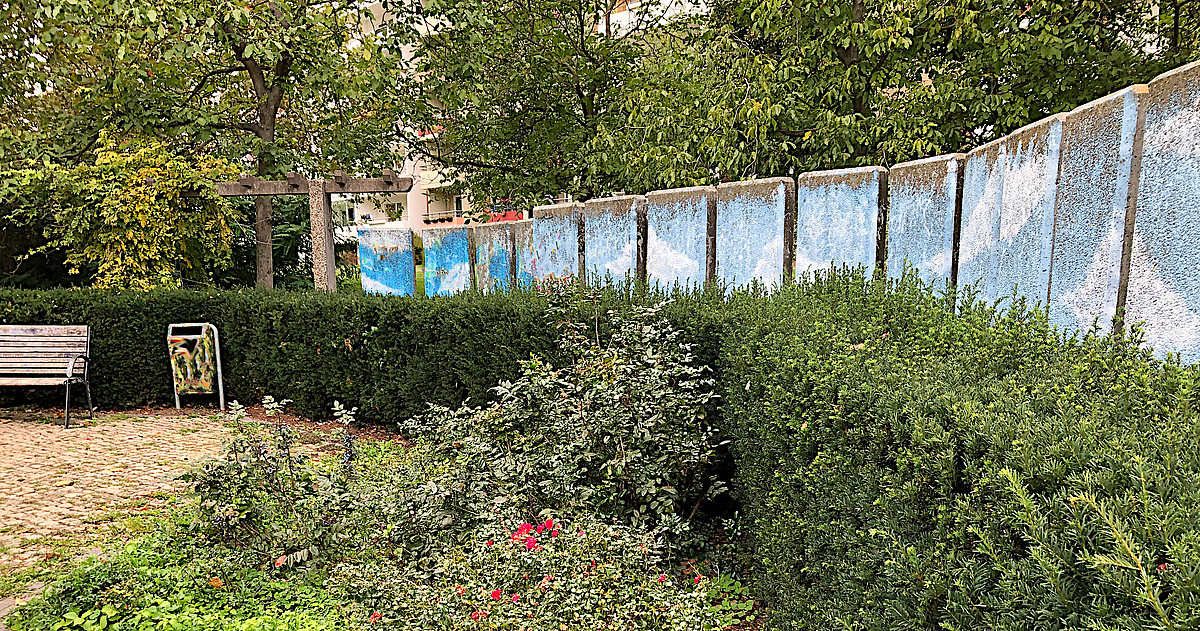 Wand aus blau bemalten Betonelementen, davor bepflanzung
