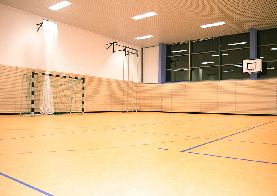 Sporthalle mit hellem Boden, umlaufenden Holzpaneelen, Fußballtor