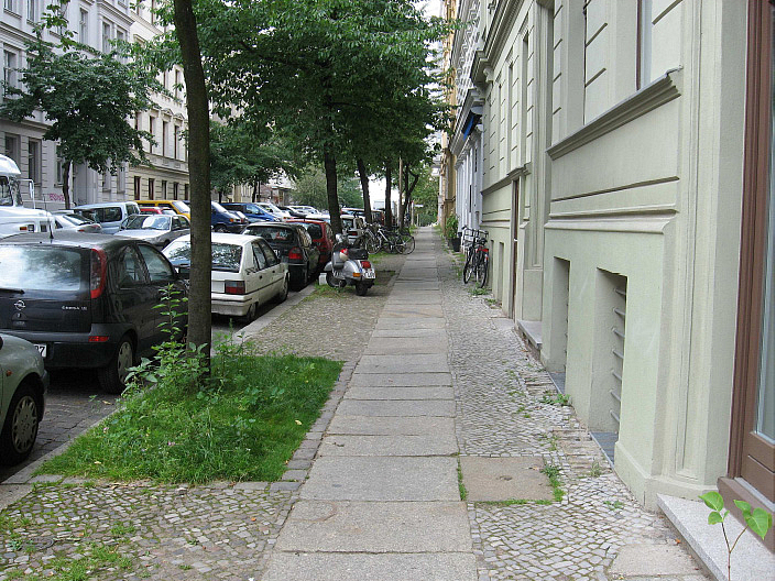 Gehweg in begrünter Wohnstraße mit Baumscheiben