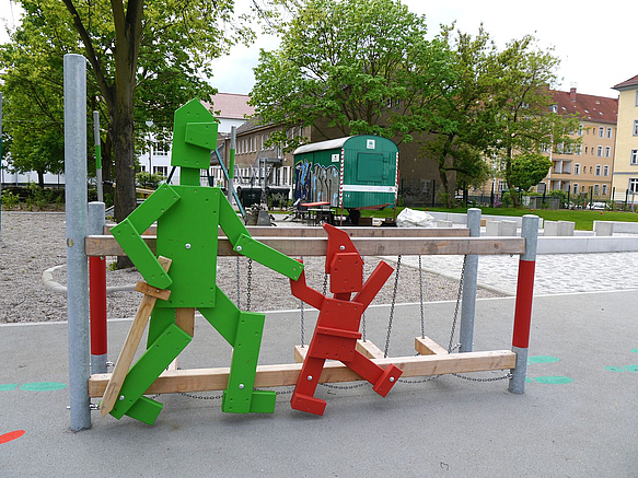 Große grüne Ritter- und rote Zwergenfigur an Balanciergerät
