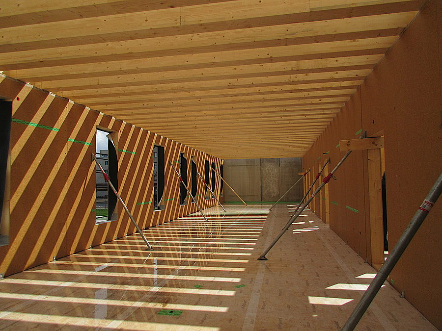 Raum mit Holzboden, Holzfaserwänden und Holzplatten mit Stützen für die Wände