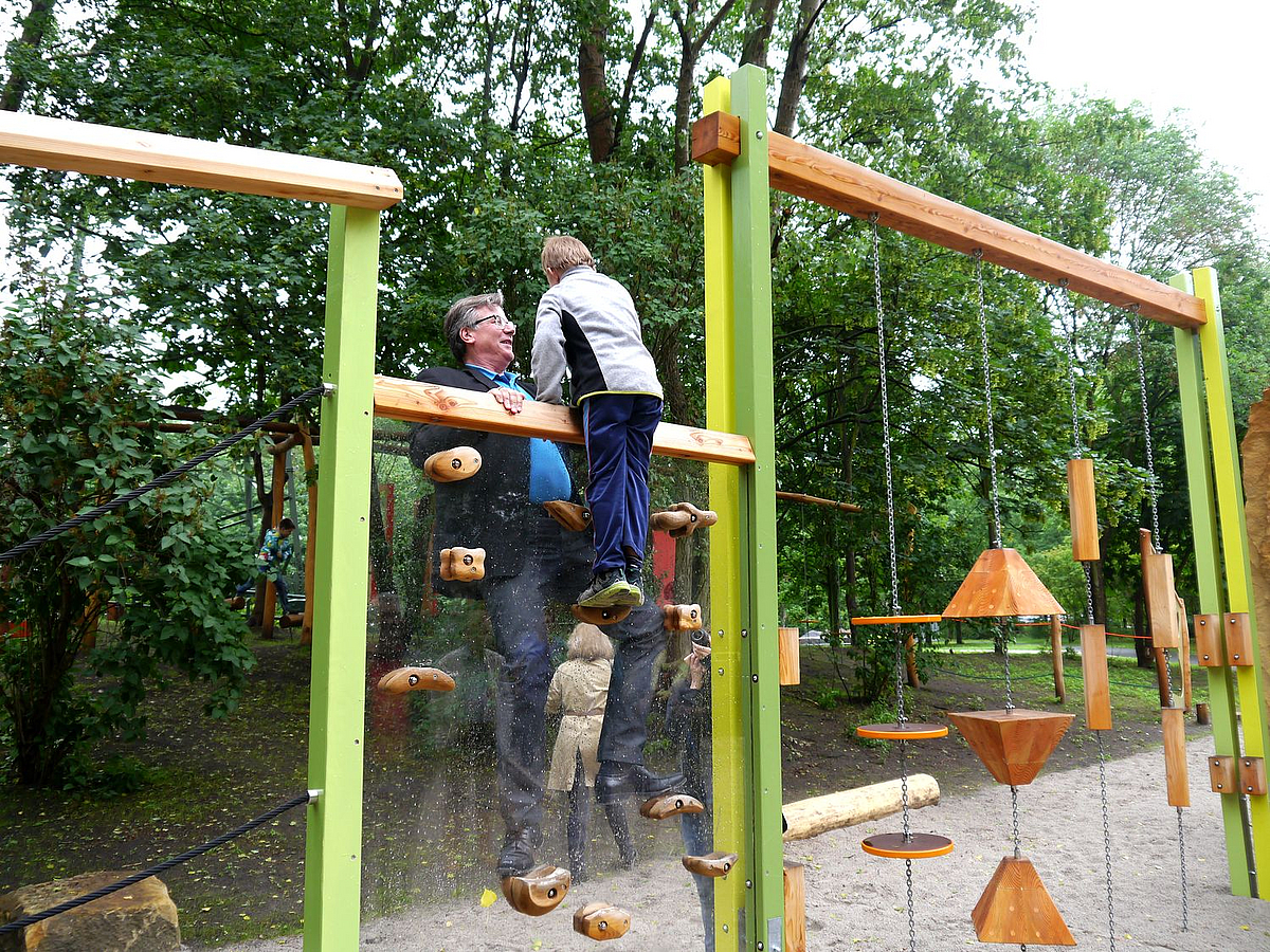 Mann und Kind klettern an beiden Seiten einer senkrechten Plexiglaswand
