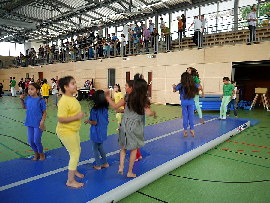Kinder hüpfen auf Matte in Sporthalle