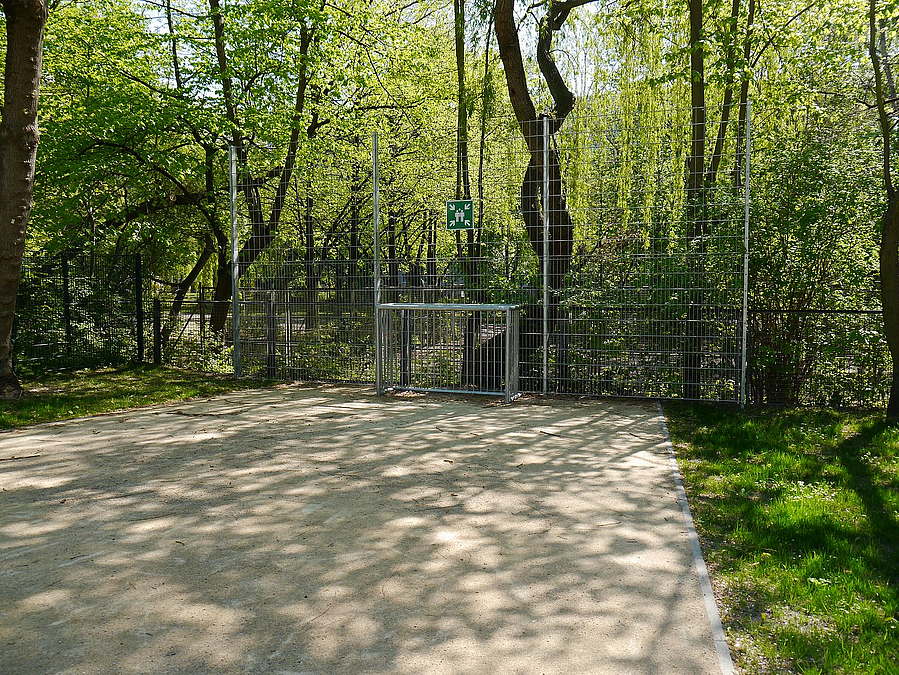 Kleines Tor auf wassergebundener Fläche inmitten von Grün