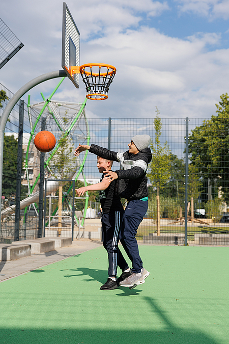 2 Jungs springen am Basketballkorb