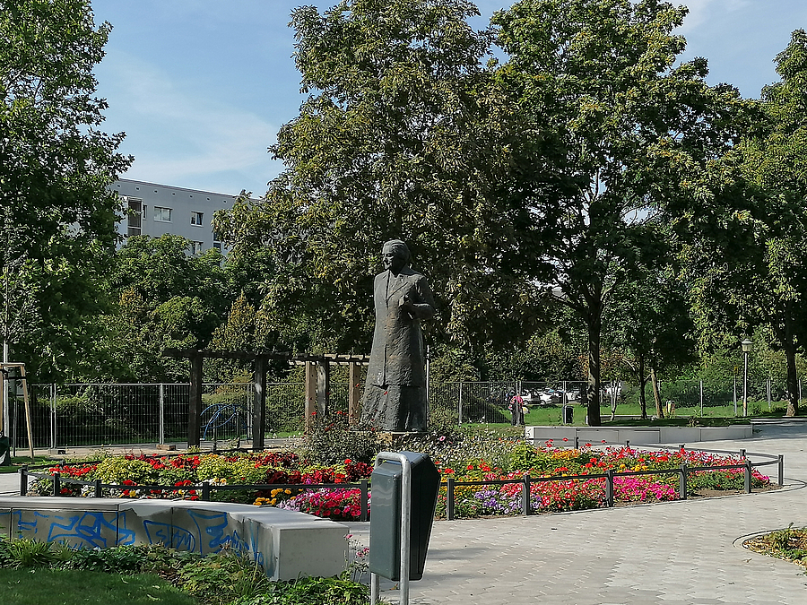 Frauenstatue in Blumenbeet, Wege, Sitzmauer
