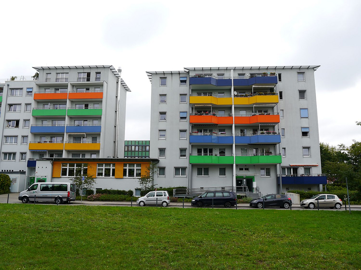 Zweigeteiltes, weißes Gebäude mit farbigen Balkons