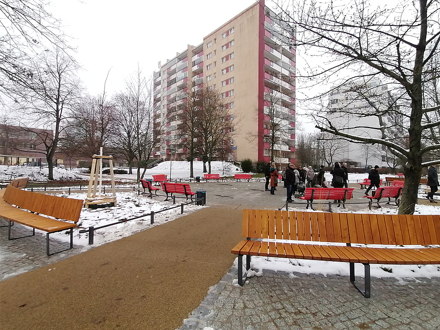 Gelber Weg, lange, halbrunde Bänke, rote Bänke, Hochhaus im Winter