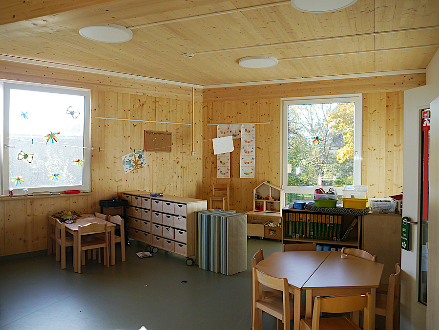 Raum mit großen Fenstern, Decken, Wänden und Möbeln aus hellem Holz
