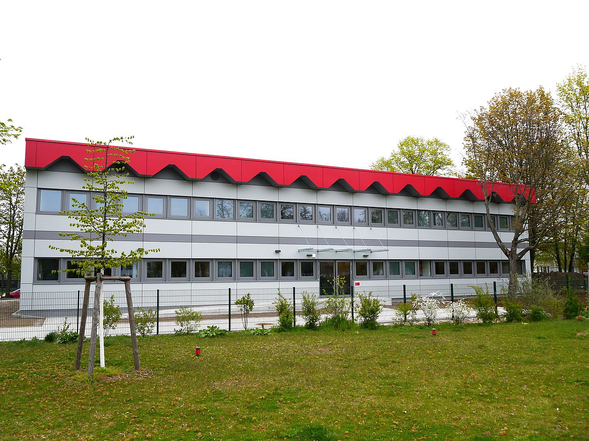 heller Flachbau mit roten Faltendach, 2 durchgehende Fensterreihen