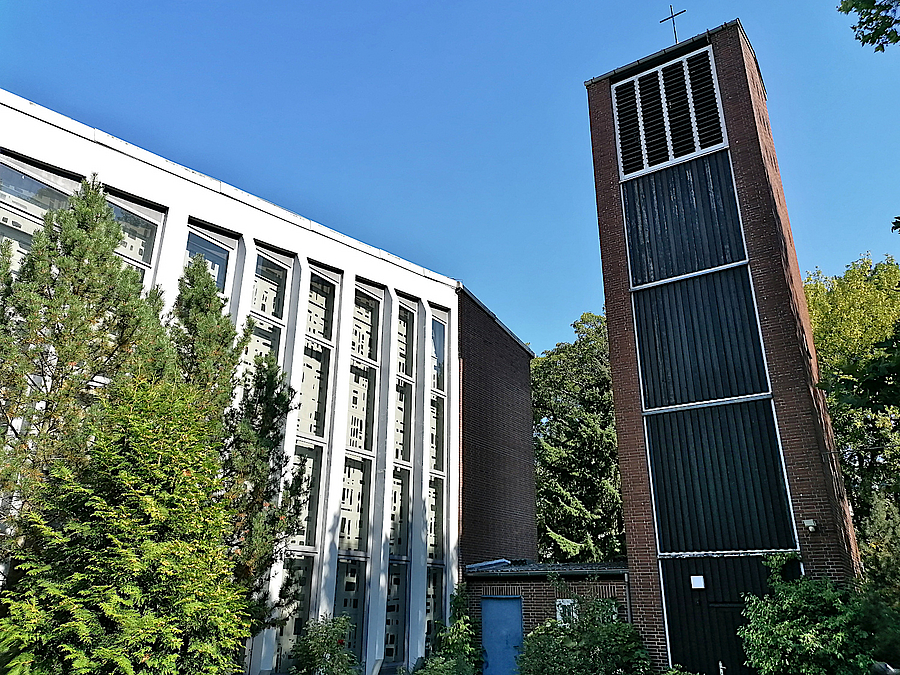 Moderner Kirchturm aus Backstein und Haus mit vertikal verlaufenden, fassadenhohen Fensternischen