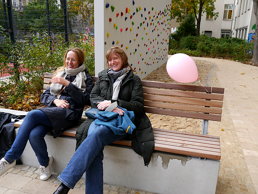2 Frauen auf einer Bank mit Luftballon, dahinter Boulderwand
