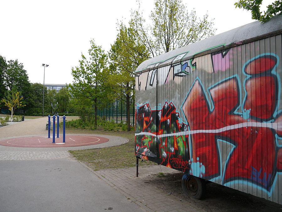 Bauwagen mit Graffiti an Weg mit Fitnessgerät