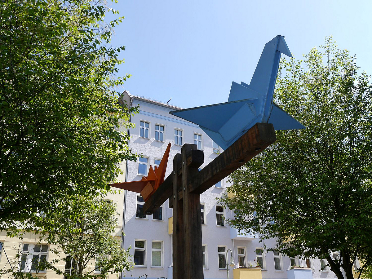 Faltkraniche aus Holz als Symbol am Eingang des Spielplatzes