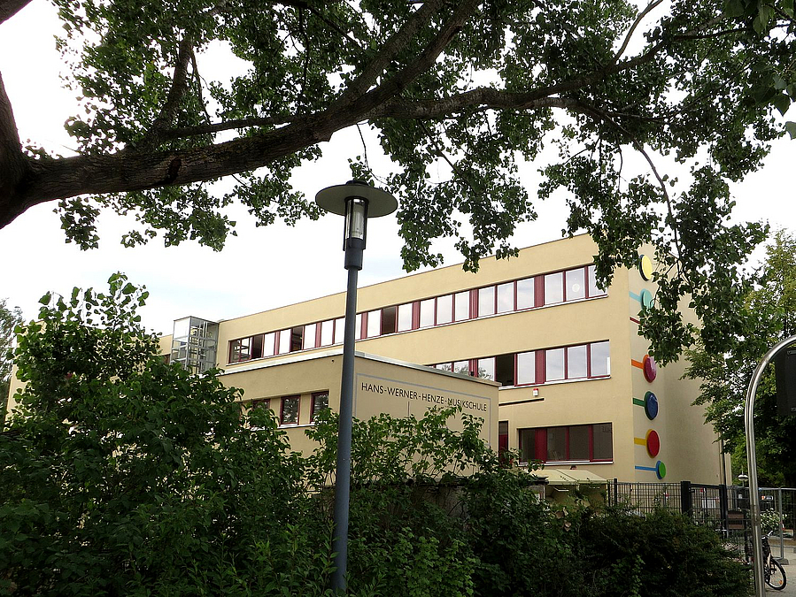 Neu verputztes Schulgebäude ist durch viel Grün zu sehen