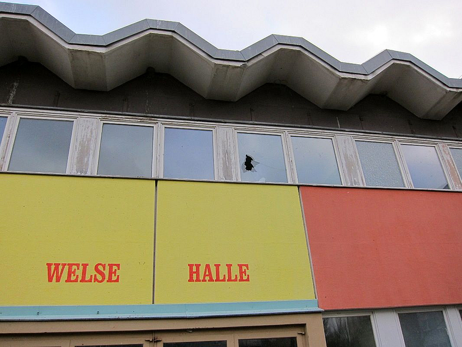 Detail über dem Eingang in gelb-rot mit Schriftzug Welse Halle