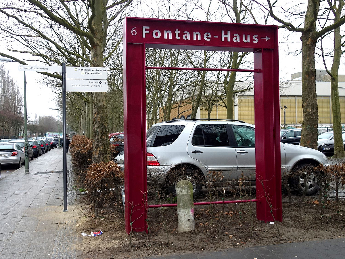 Rotes Stahltor vor Parkplatz mit Inschrift Fontane-Haus