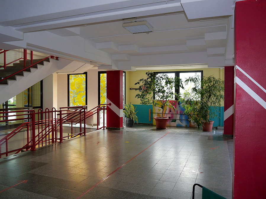 Foyer, Treppen, rote Akzente, Grünpflanzen, strukturierte Decke