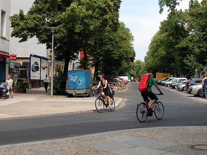 Einmündung Wohnstraße, verengte Fahrbahn, 2 Radfahrende