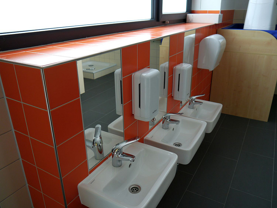 Waschbecken in unterschiedlichen Höhen an orange gefliester Wand