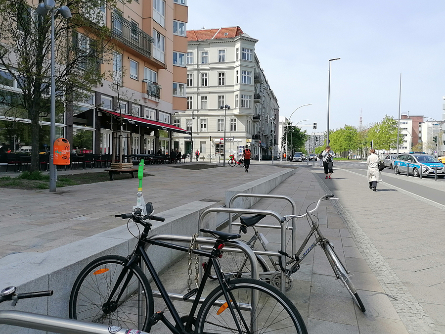 Straße mit breiten Gehweg und höher gelegener Terrasse, Restaurant, Fahrradbügel