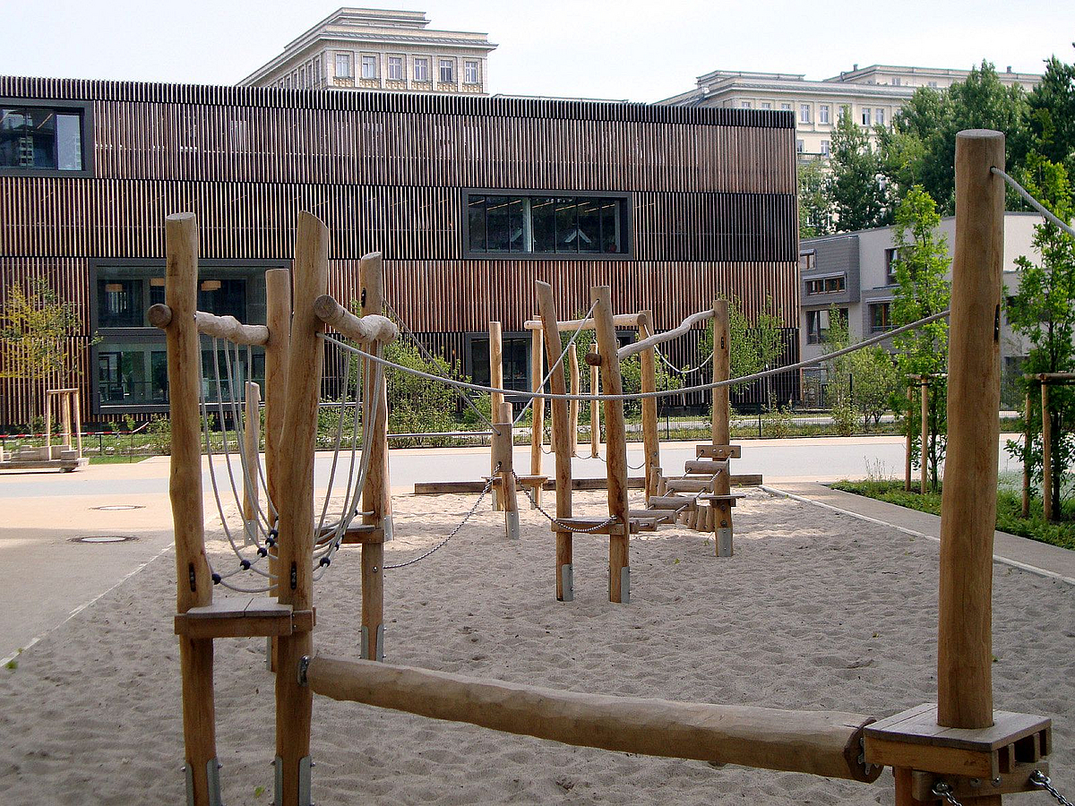 Balancierstrecke auf Sandfläche, im Hintergrund Bibliothek mit Holzlamellenfassade