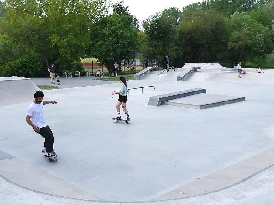 Betonfläche mit Skateboardfahrern und Inline-Sportlern