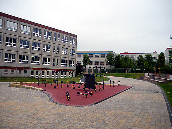 Plattenbauschule, geklinkerter Platz, in der Mitte Sportfeld mit Geräten