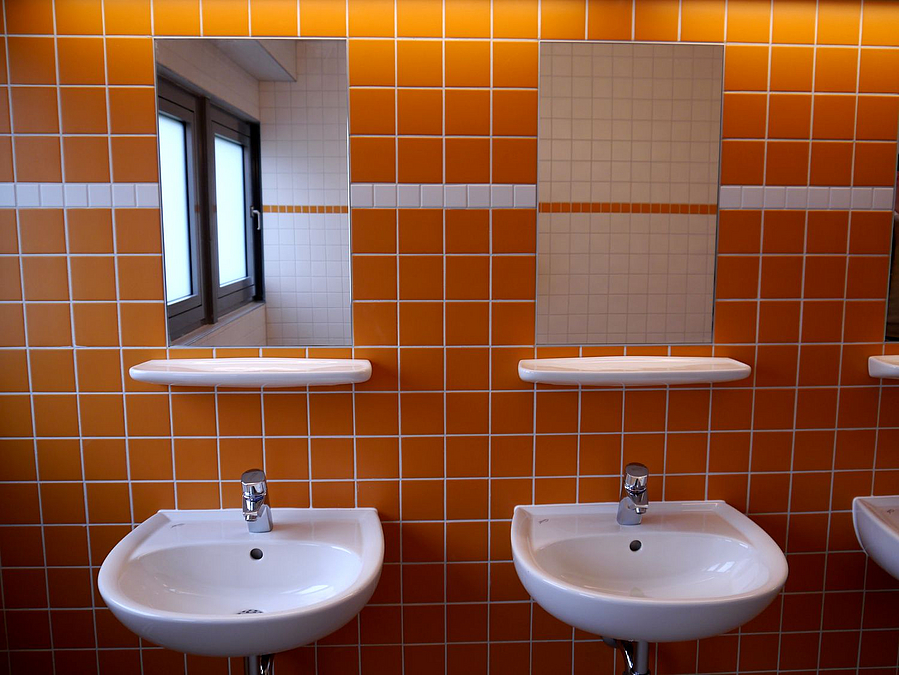 2 Waschbecken mit Speigel vor orange gefliester Wand