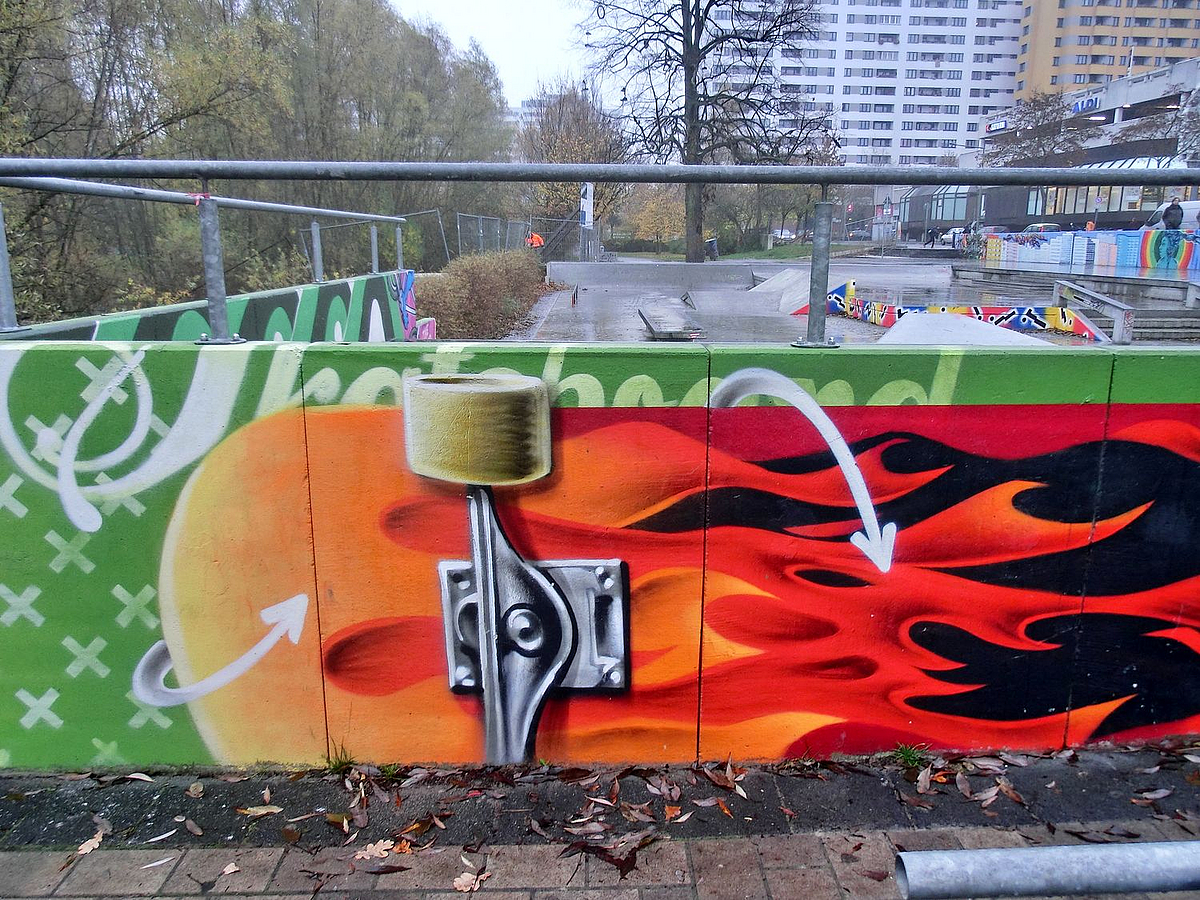 Betonmauer mit Geländer und Wandbild: Skateborad im Feuerdesign
