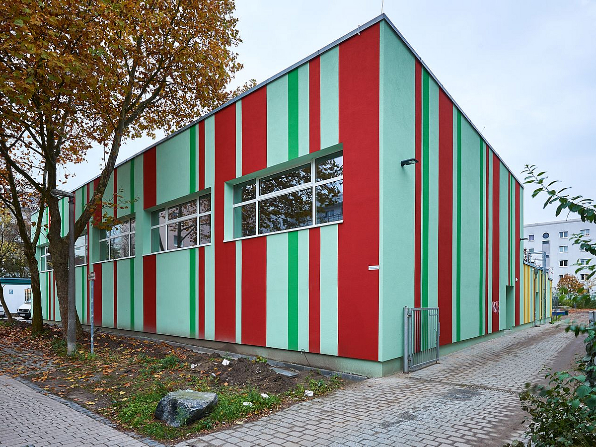Fassade mit vertikalen roten, hellgrünen und grünen Streifen unterschiedlicher Breite
