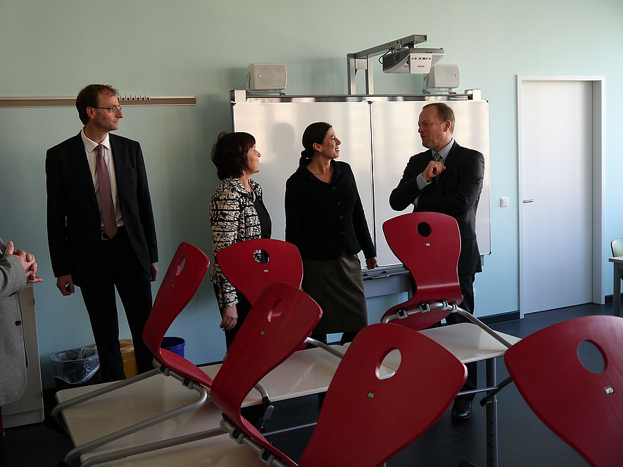 im Klassenraum vor Smartboard und hochgestellten roten Stühlen